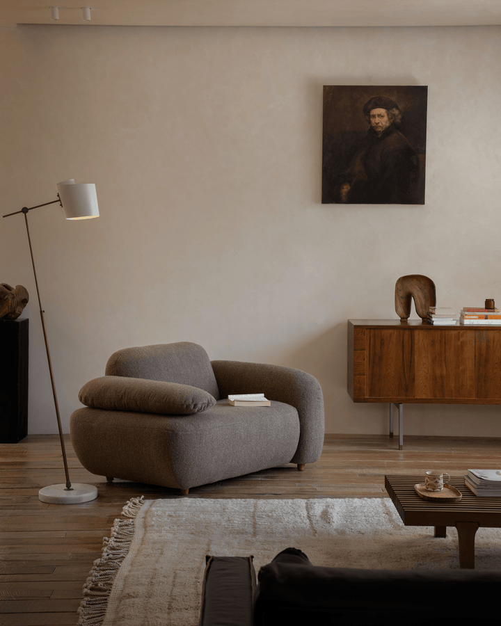 Cozy brown Gestein Bouclé Armchair in modern living room with wooden decor and artwork.