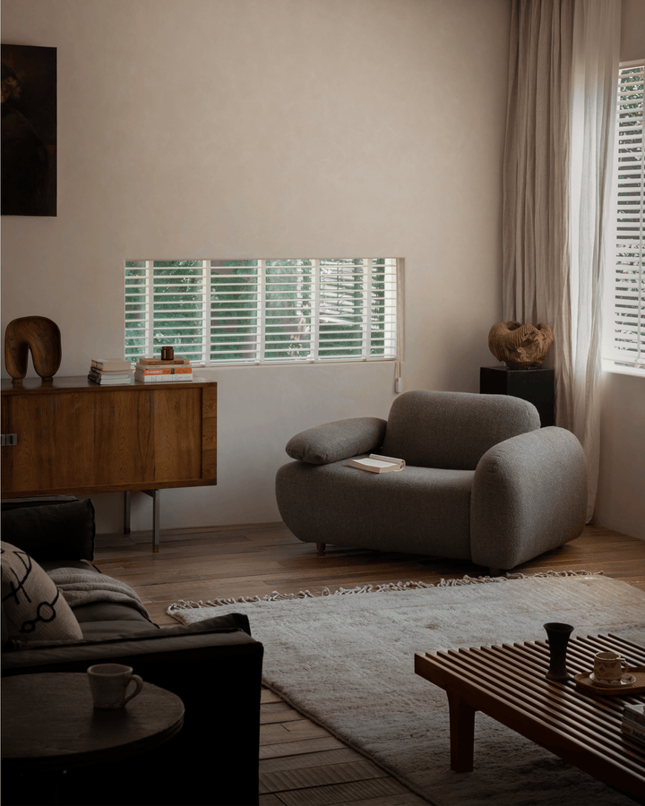 Gestein Bouclé Armchair in gray fabric placed in a cozy living room with warm decor
