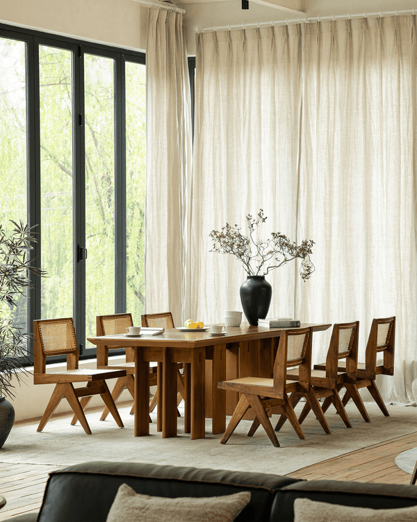 Stylish wooden dining table with six chairs and a vase in bright natural light