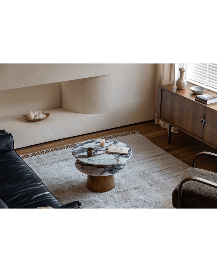 Elegant round table with marble top and wooden base in contemporary living room.