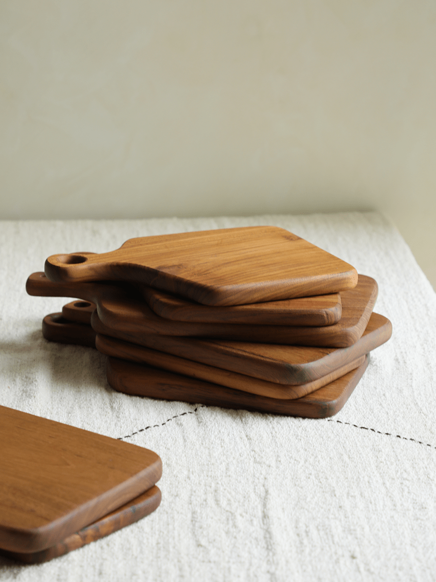 Stacked wooden cutting boards with handles, natural wood grain on white surface.
