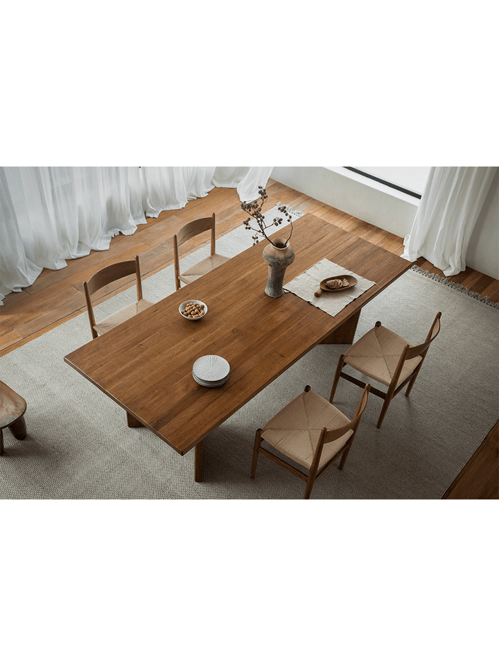 Zephyr dining table of reclaimed wood with decorative vase and woven chairs in bright room