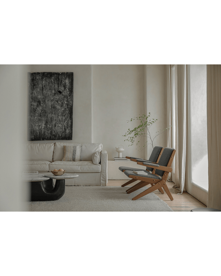 Two gray Scissors Chairs with wooden frames next to a recliner sofa in a minimalist living room.