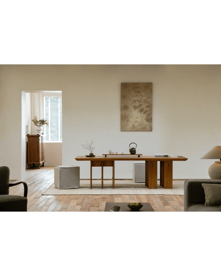 Modern teak dining table set in a bright, minimalist interior with soft furnishings.