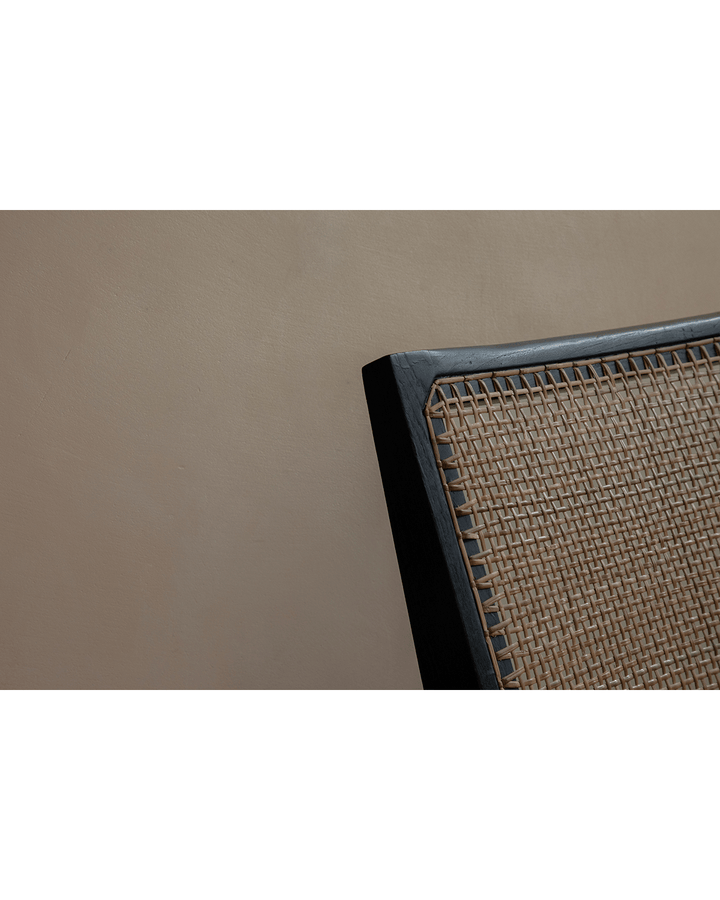 Detail of Chandigarh Armless Easy Chair's woven rattan backrest against a smooth wall