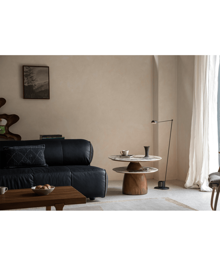 Elegant round side table with glass top and wooden base in a modern living room.
