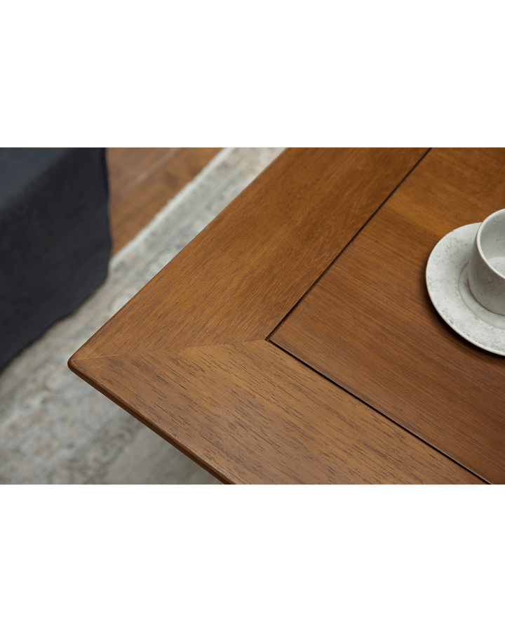 Close-up of teak table corner with a ceramic cup and saucer.