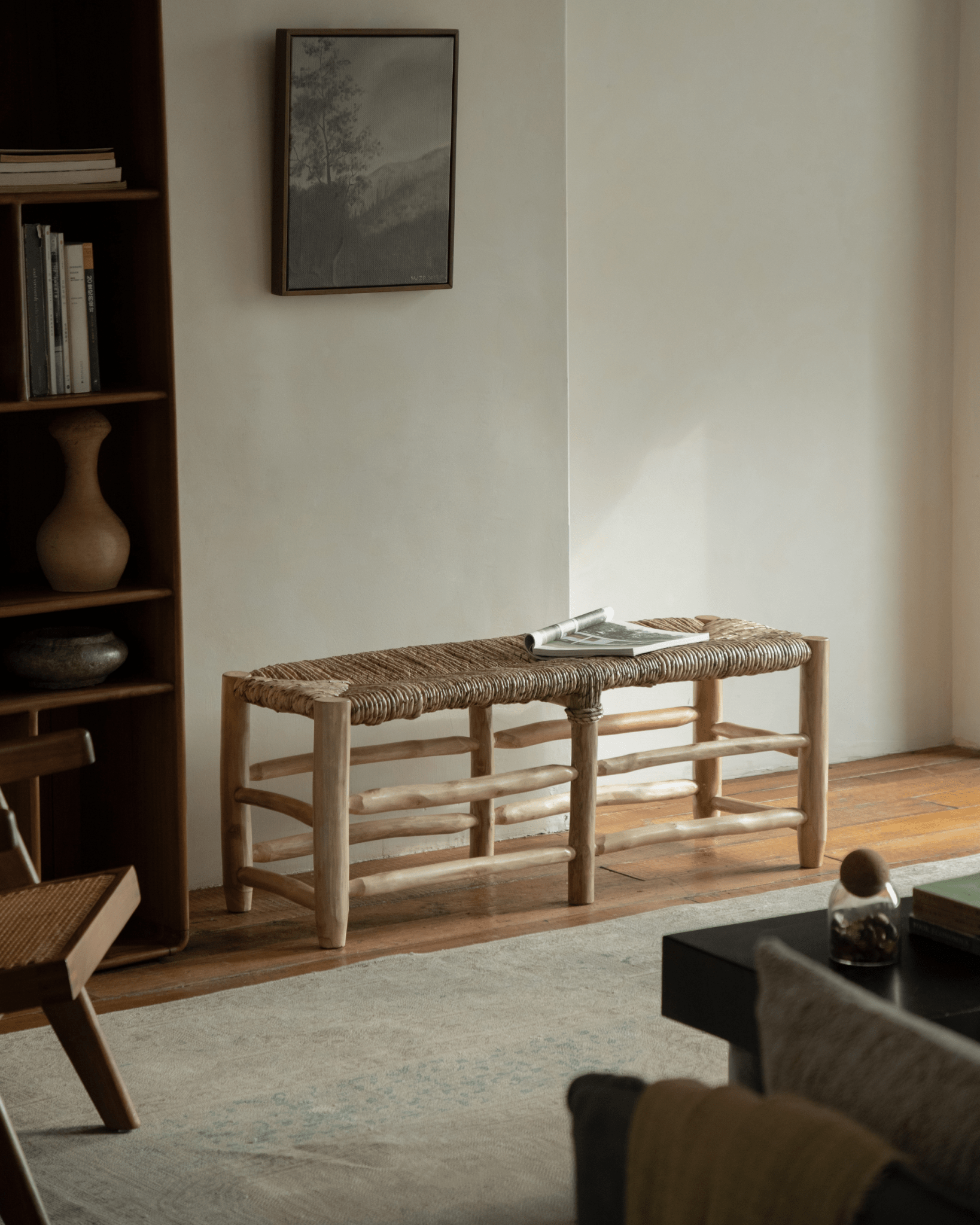 Isla Bench in a room setting, showcasing teak frame, woven pandan leaf seat, and modern organic design