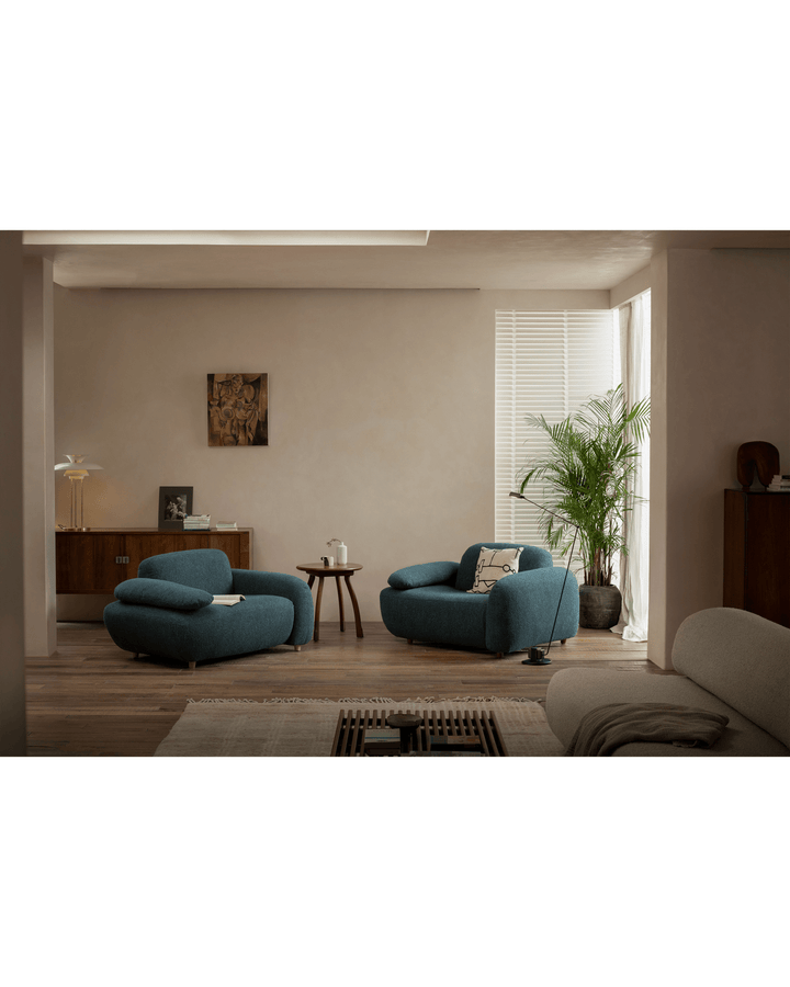 Modern living room with Ele Round Side Table, teal armchairs, and large window.