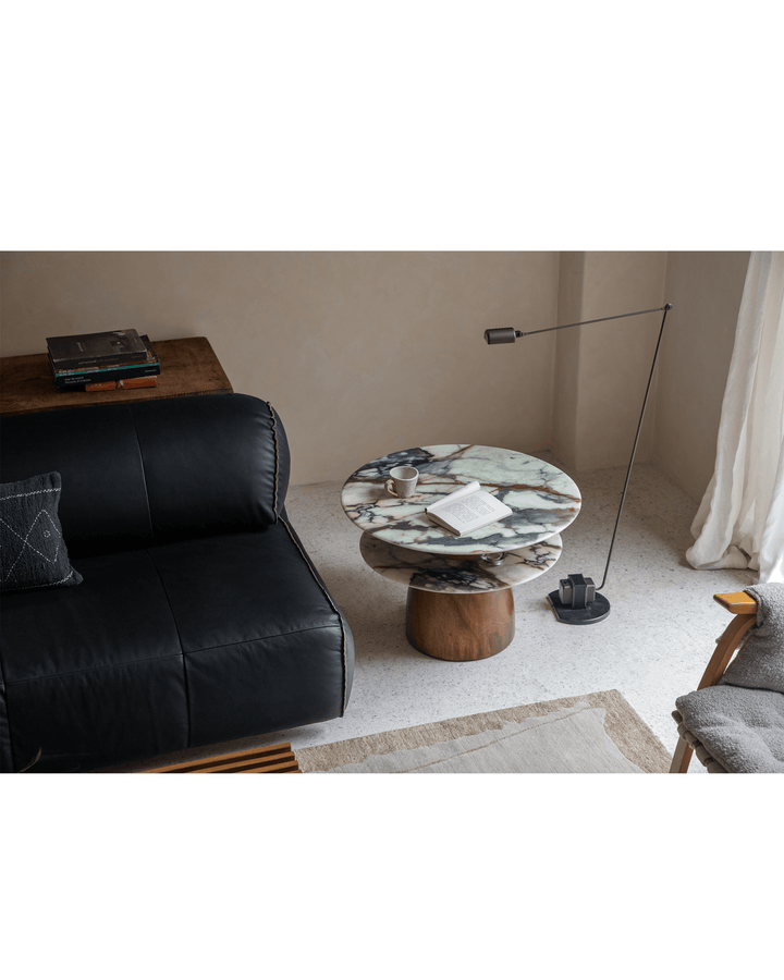 Round side table with artistic marble top and wooden base in modern living room.