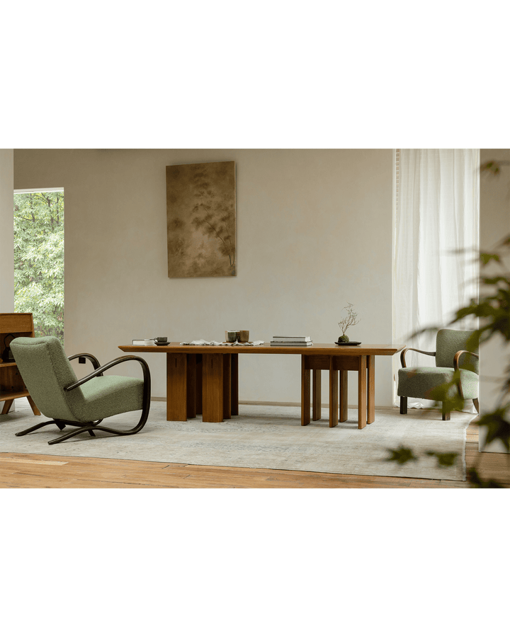 Titan teak dining table with multi-leg design and green chairs in bright interior.