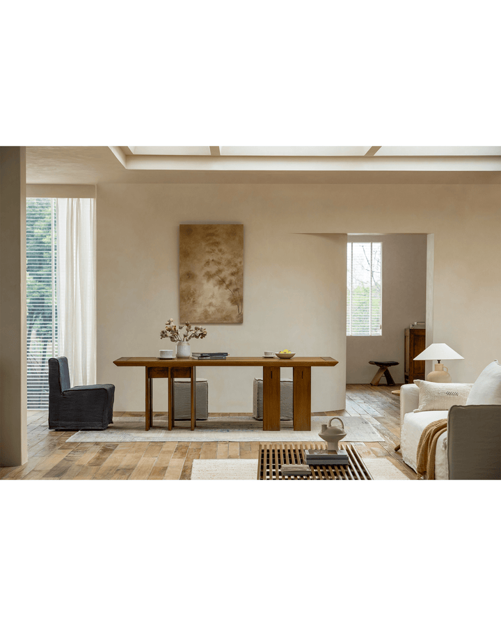 Modern teak dining table with a vase and soft chairs in bright minimalist interior