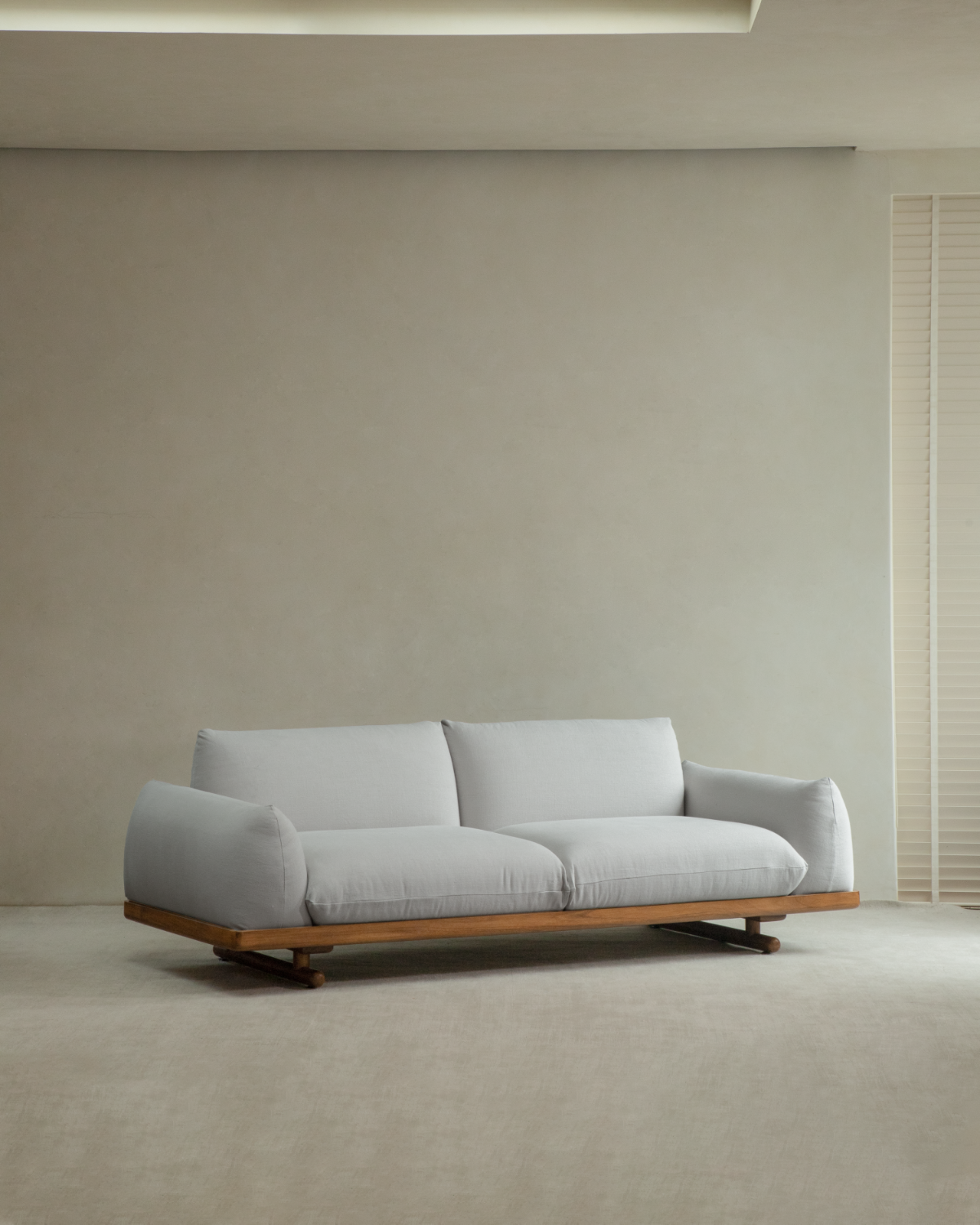 Adrian Sofa with light gray linen upholstery and teak wood base in a minimalist living room