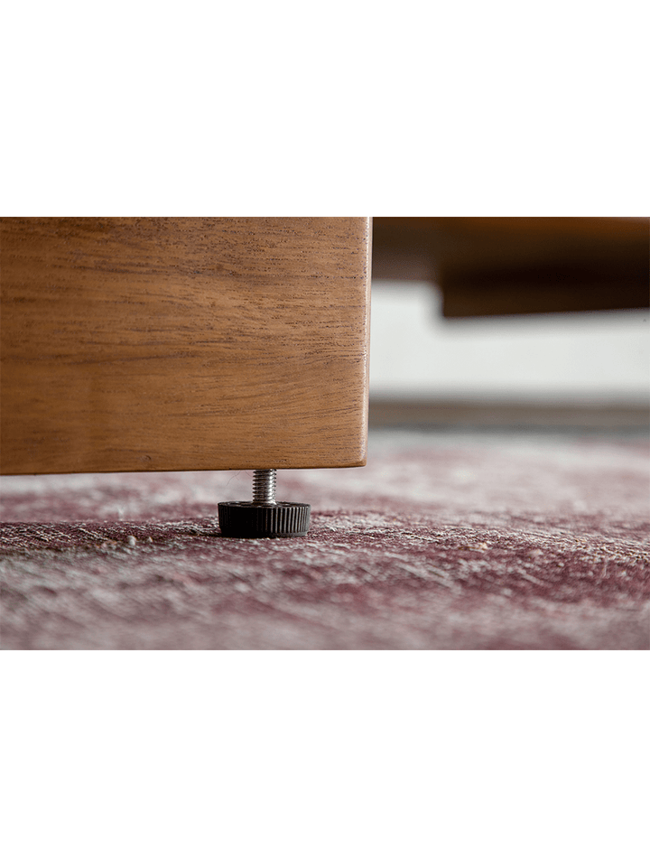 Teak sofa base with adjustable foot support, ensuring stability on carpet.