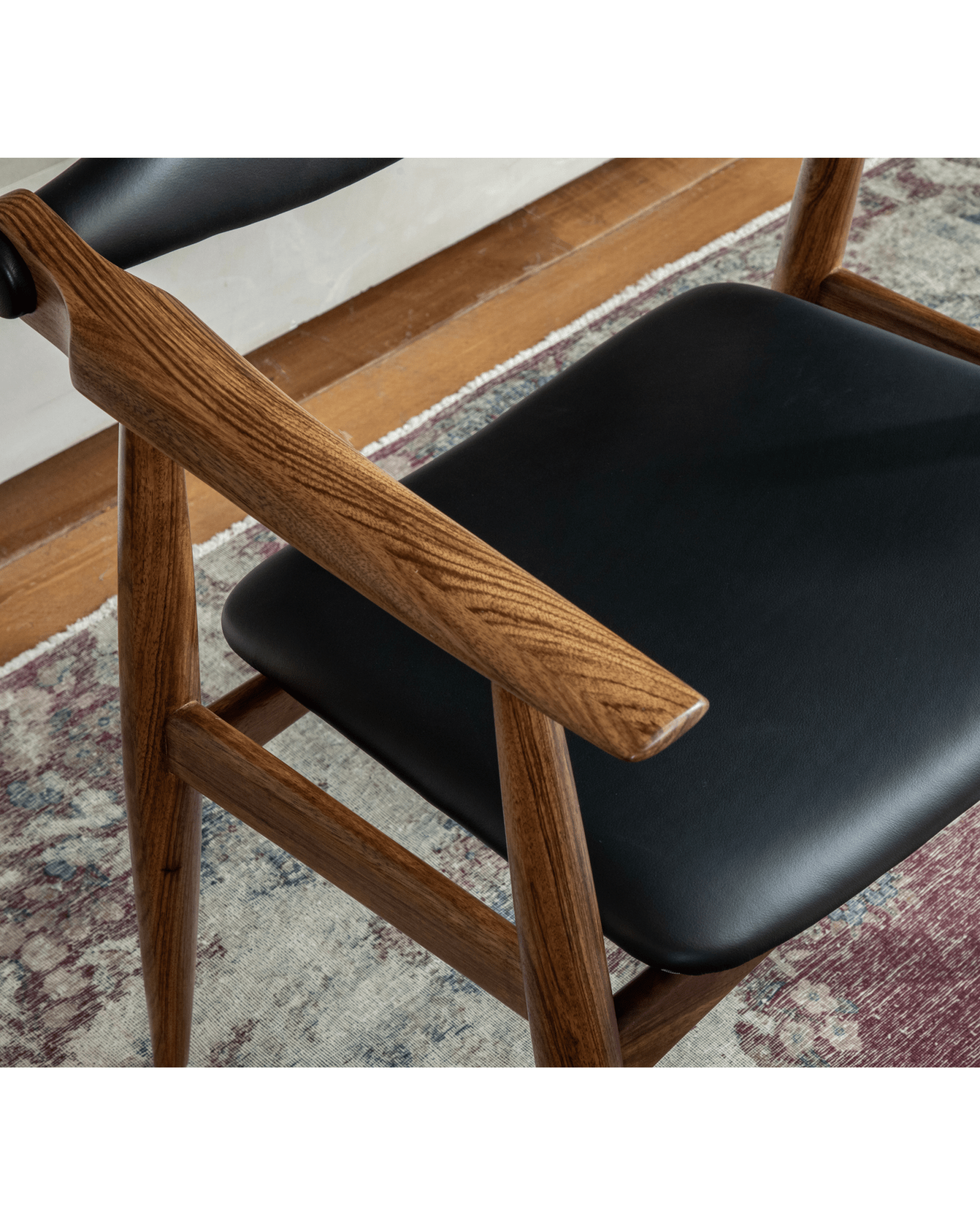 CH34 Yoke Chair detail: Ebony wood armrest and seat with black leather upholstery, mid-century modern design.