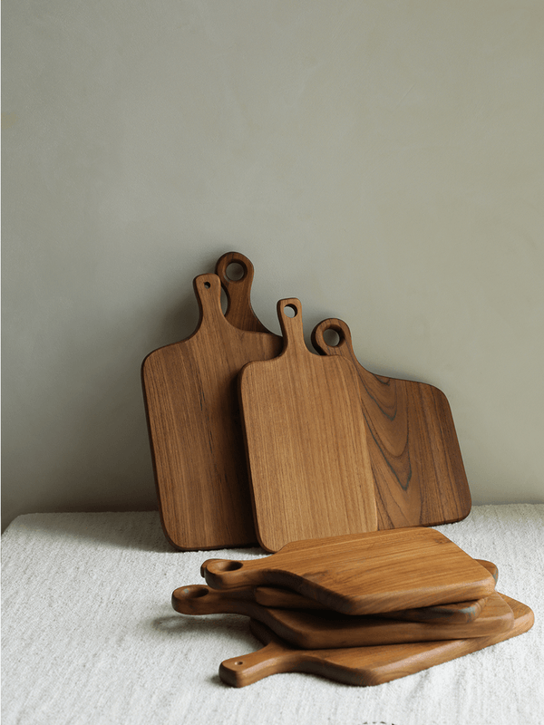 Collection of wooden cutting boards with handles on a neutral background