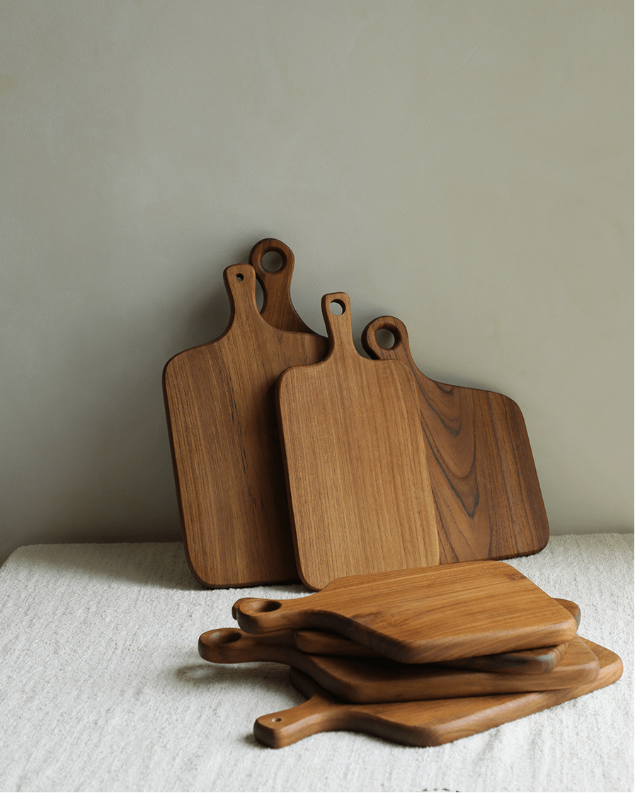 Warm-toned teak cutting boards, handcrafted, with integrated handles.