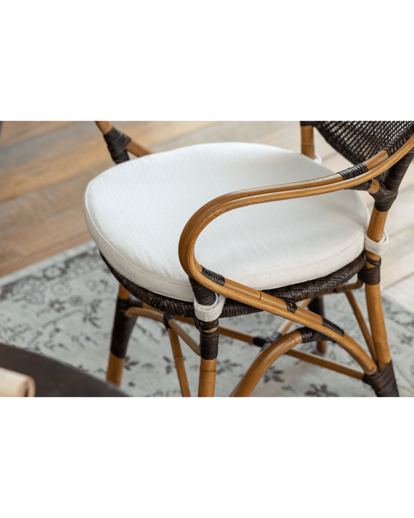 Areca Rattan Chair detail: Handwoven rattan armrest, white cushion, and natural brown finish