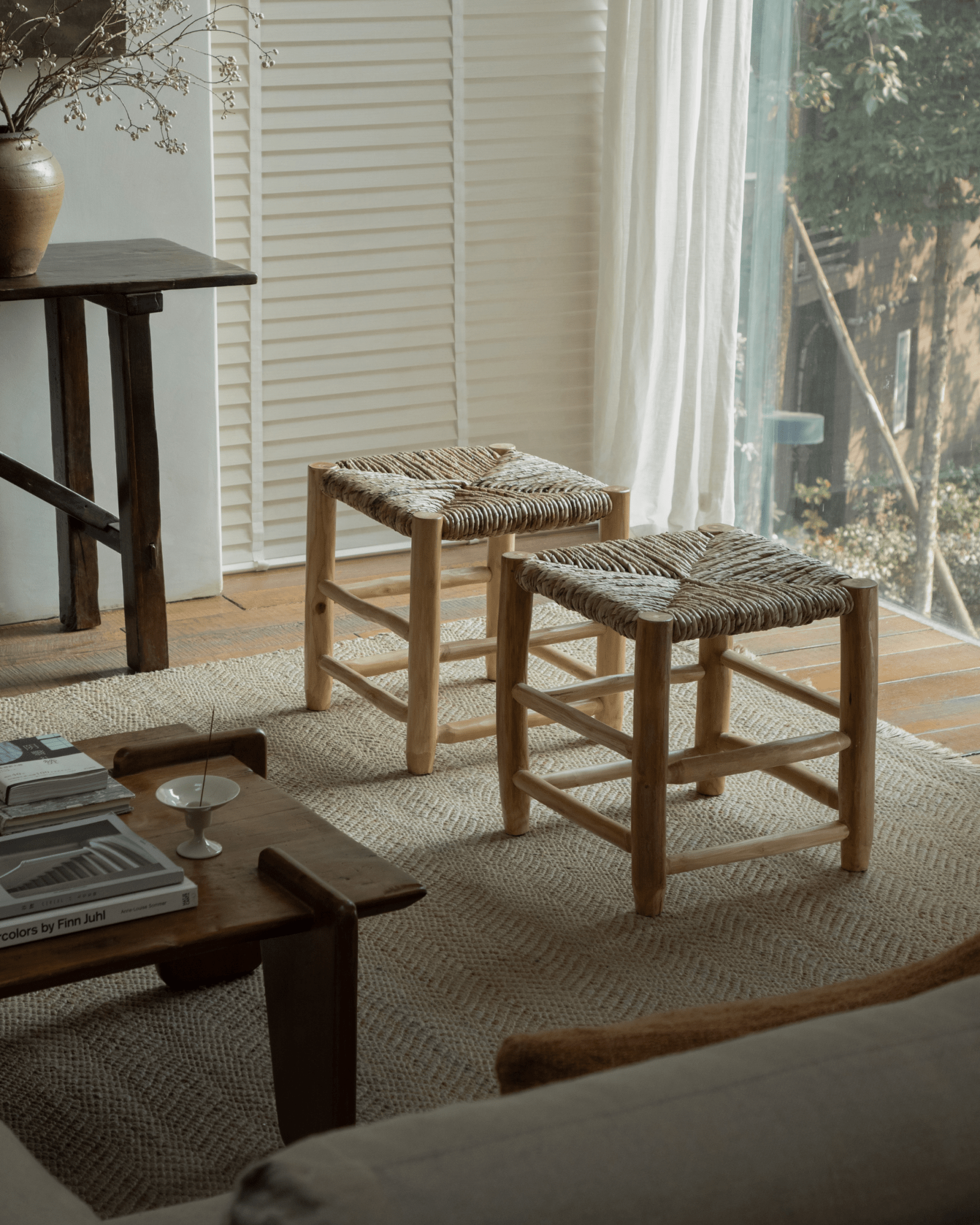 Isla Handwoven Stool set in a living room, featuring natural wood frame with woven pandan seat and earthy tones.