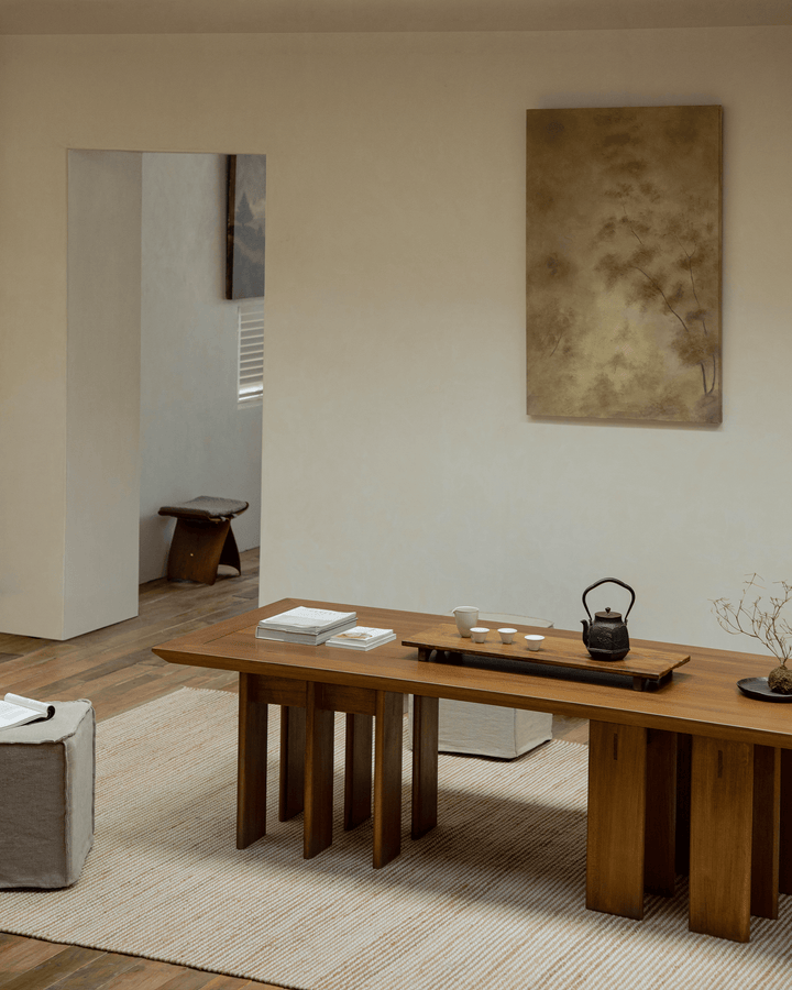 Elegant wooden multi-legged dining table with tea set in a minimalist interior.