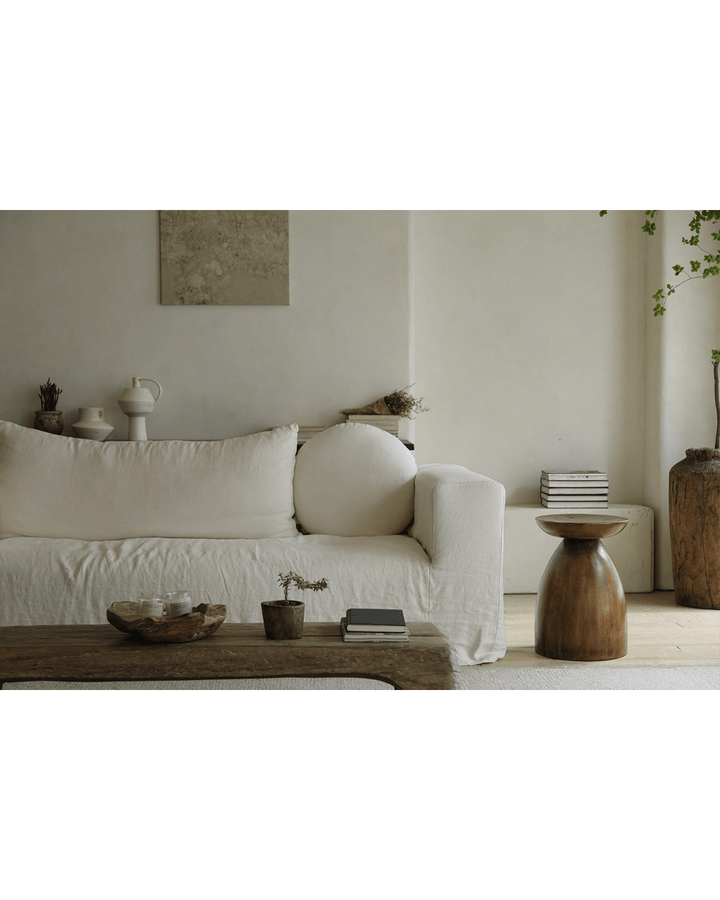 Sandglass Table beside a light sofa in a serene minimalist living room setting.