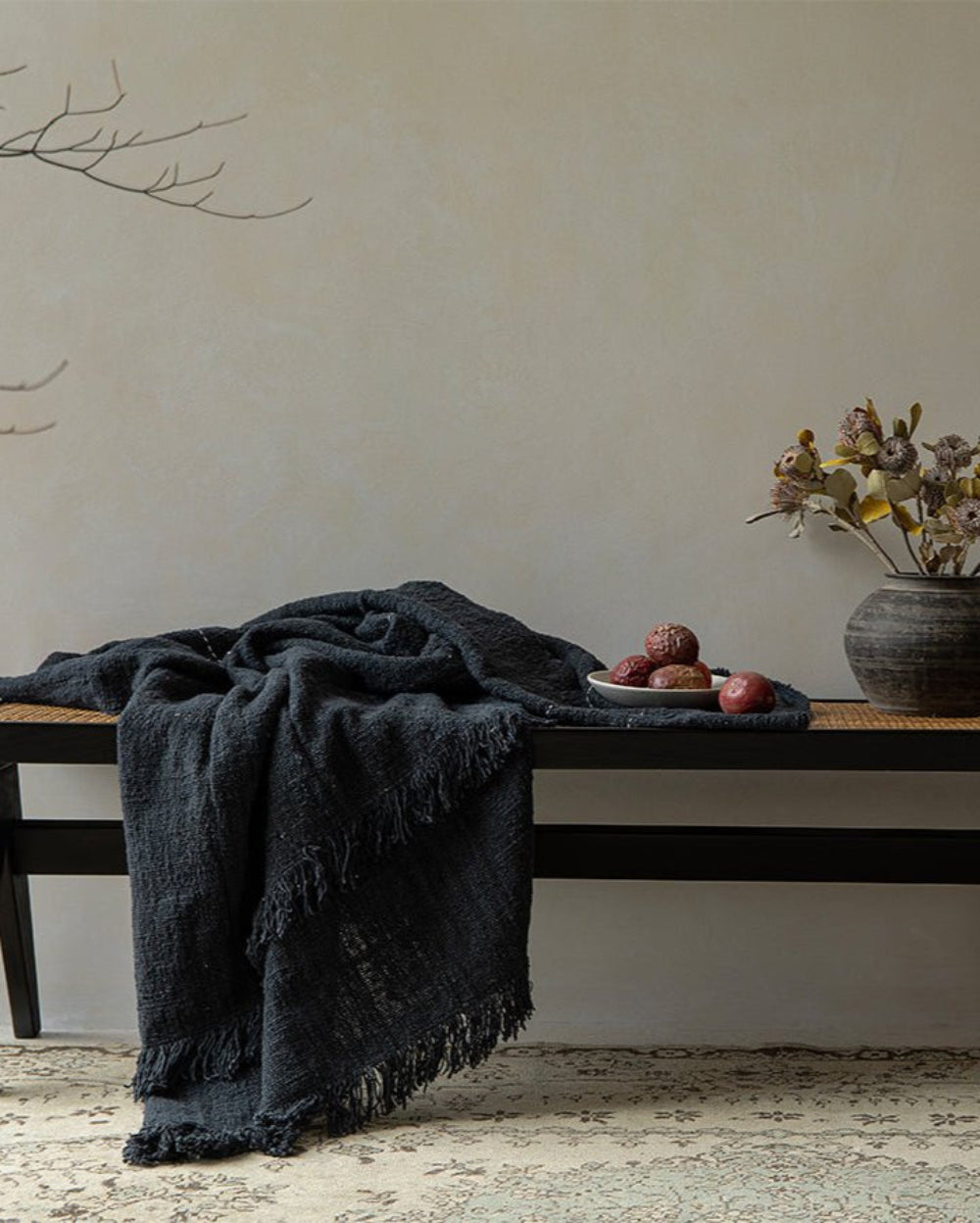 Dark gray cotton blanket with fringe on black bench, cotton throw