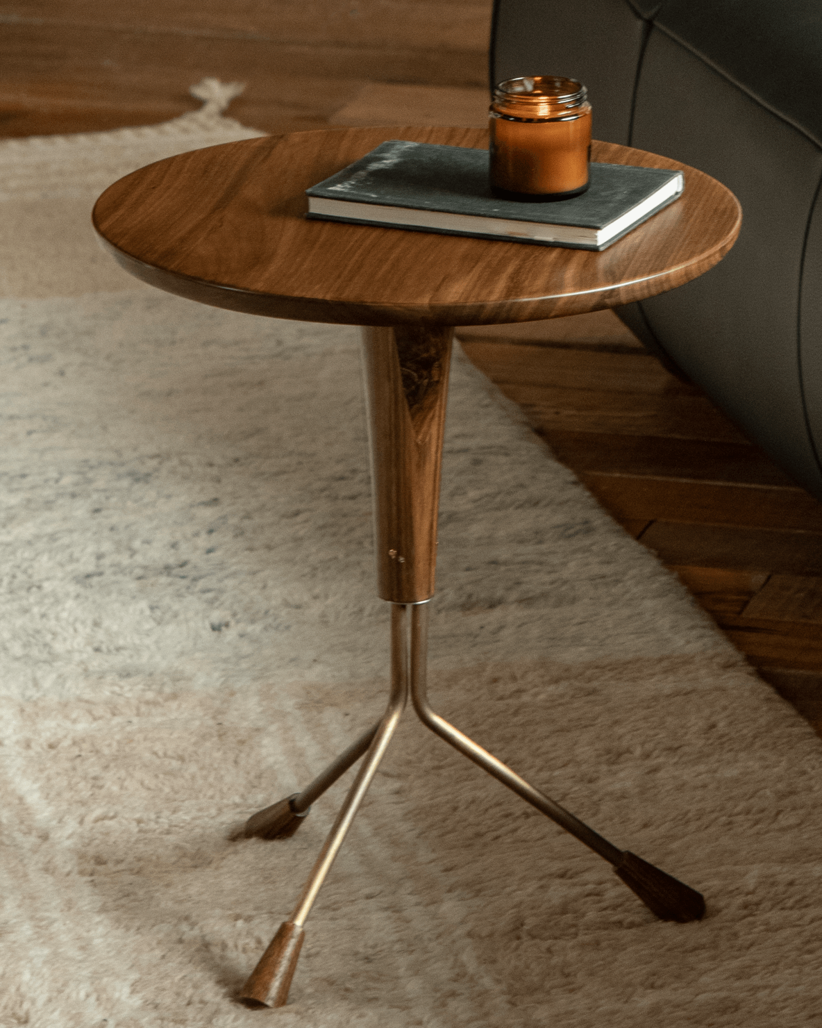 Larsson Side Table with ebony wood and Aged Brass accents, featuring a round top, supported by a tripod base.