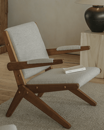 Scissors chair in light gray upholstery with red oak wood frame and unique scissor leg design.