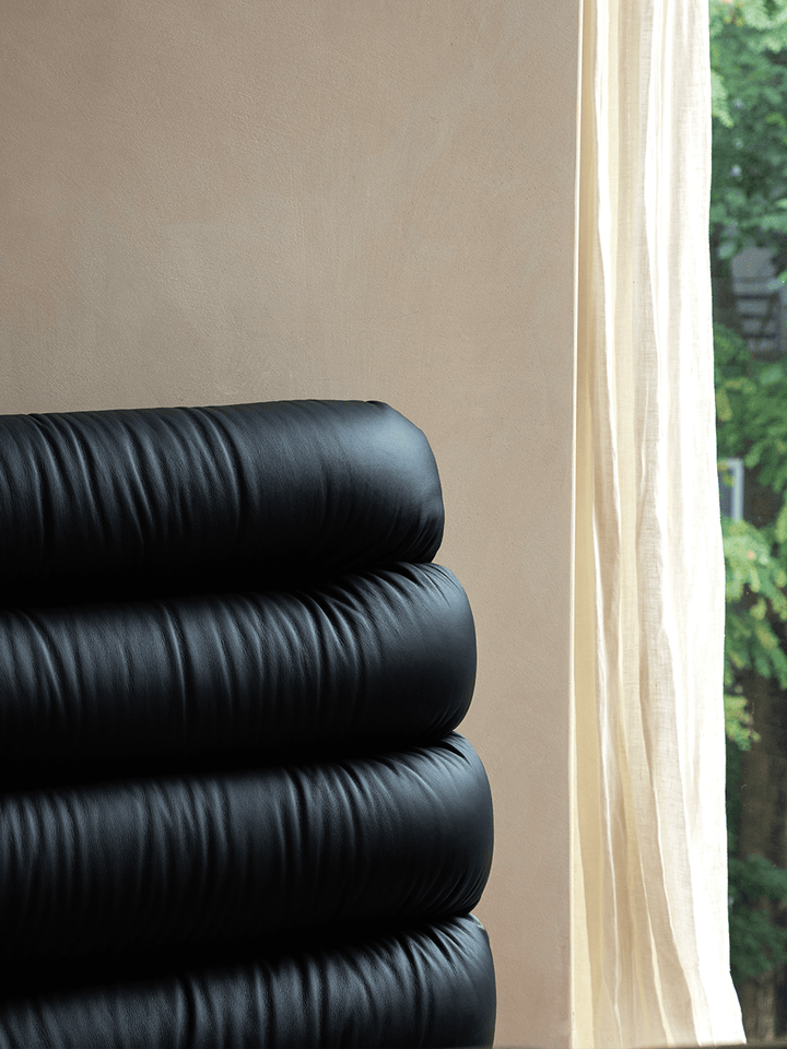 Plush black leather backrest details near a window in a modern bedroom.
