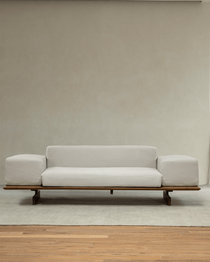 Linen modular sofa with teak wood base in a serene and minimalist interior.