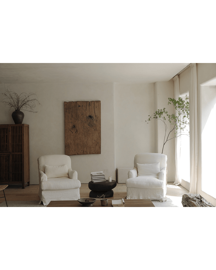 White slipcover armchair in a bright, minimalist living room with natural decor