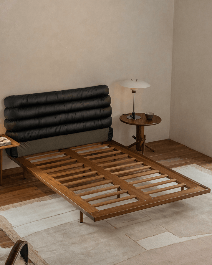 Teak bed frame with black leather backrest in contemporary bedroom