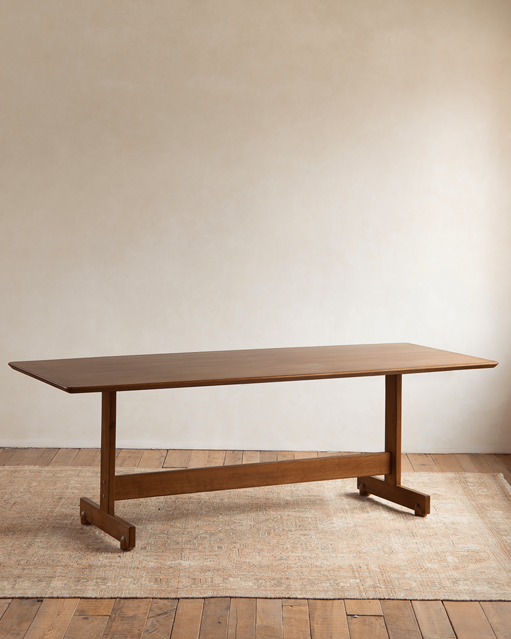 Hoof Dining Table with I-shaped base, solid wood construction in a warm brown finish, versatile for dining and working.