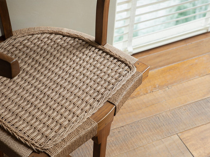 Woven seat of a teak dining chair highlighting craftsmanship and design.