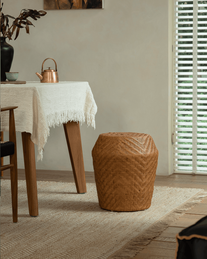 Drum Rattan Side Table beside a textured rug and dining table in a bright room