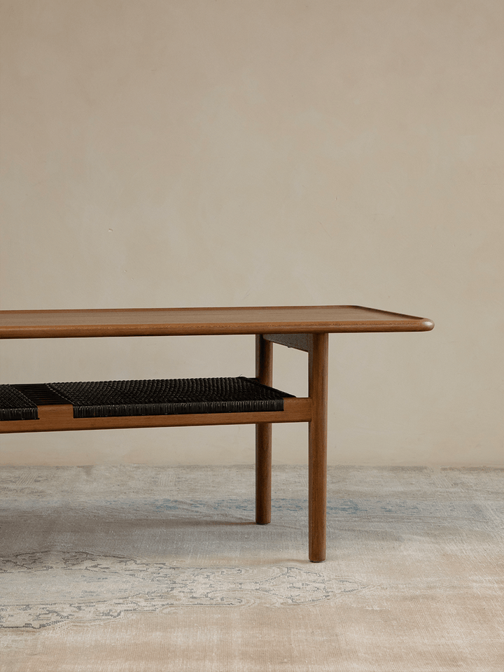 Minimalist wooden accent table with woven shelf in airy living space.