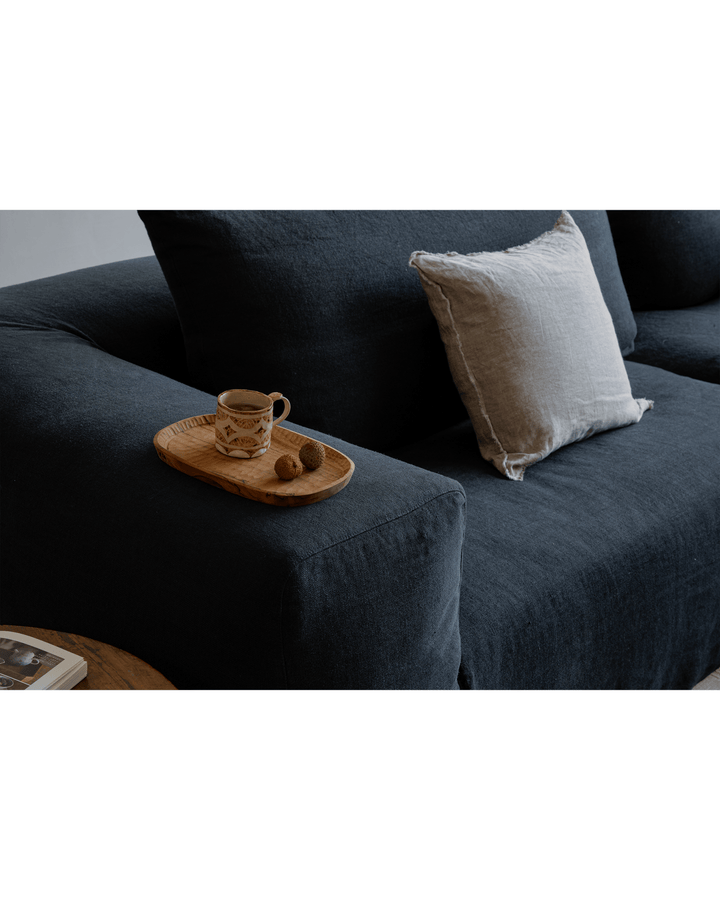Cozy dark linen Doma sectional sofa with a tray, cup, and cushion in a serene setting.