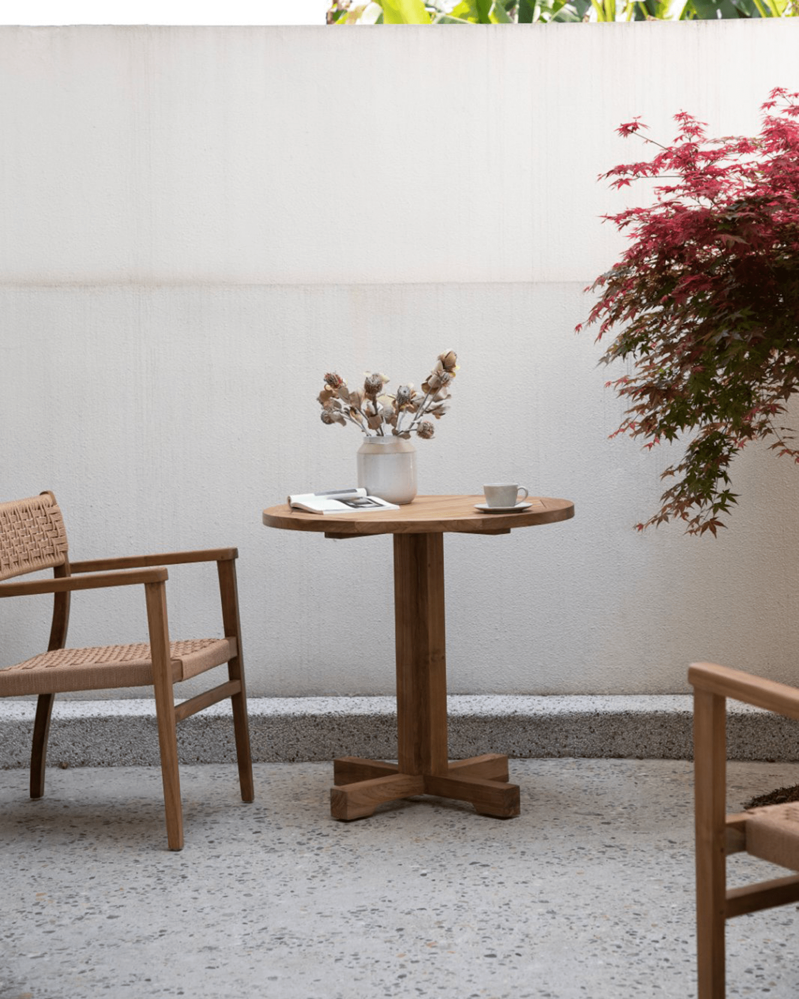 Ruby teak round table in patio setting, featuring solid wood table, wooden chair, perfect for leisure.