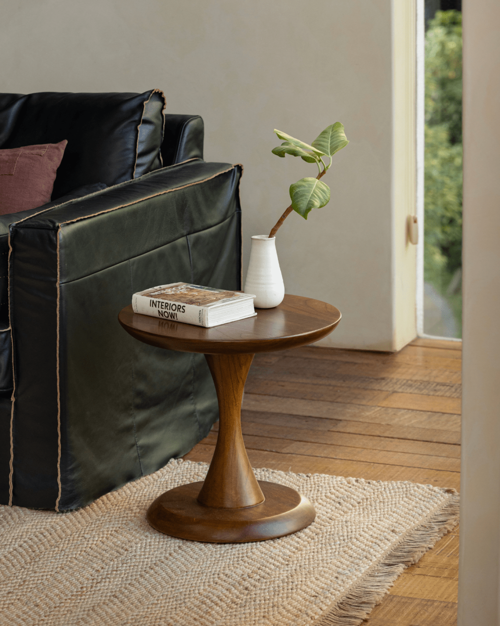 Spindle Side Table in solid teak, hourglass base, holding book. Compact side table ideal for any room.
