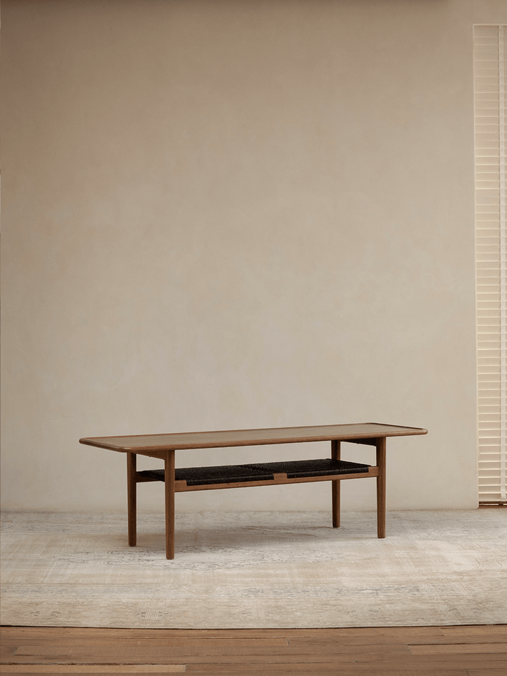 Sleek wooden accent table with shelf in minimalistic living room setting.