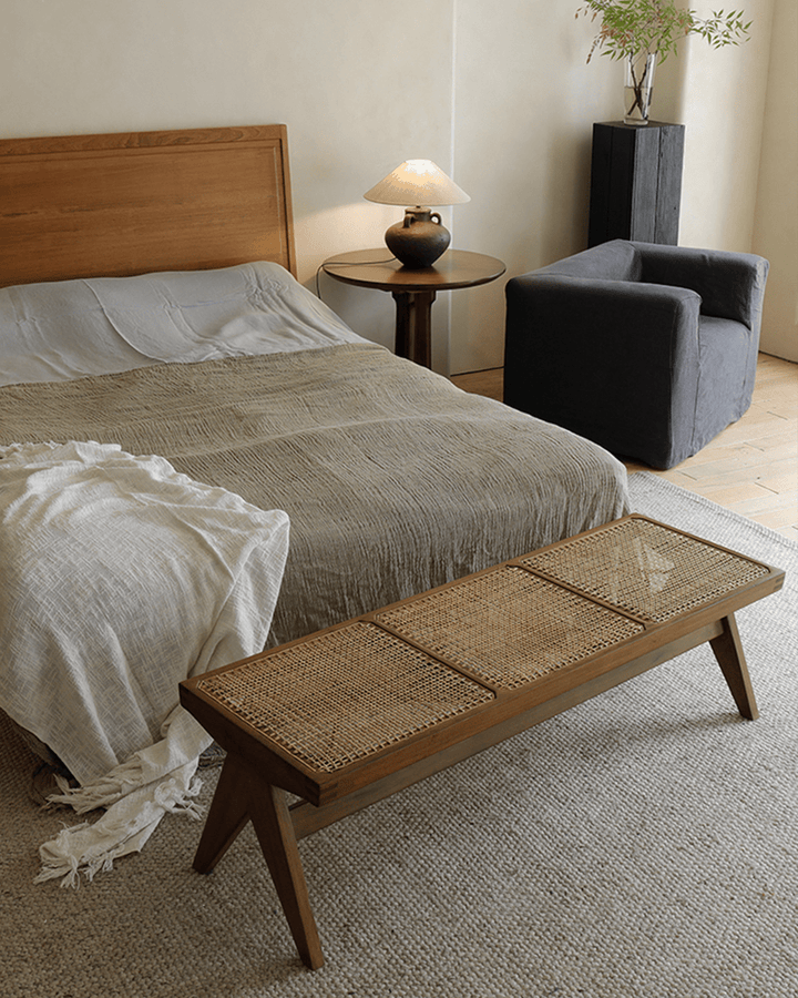 Chandigarh bench in teak wood and rattan in a cozy bedroom with soft lighting.
