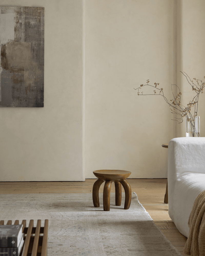 Wooden jelly stool beside a minimalist sofa in a modern vintage living room.