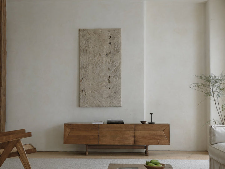 Handcrafted wooden sideboard under textured wall art in minimalist living room