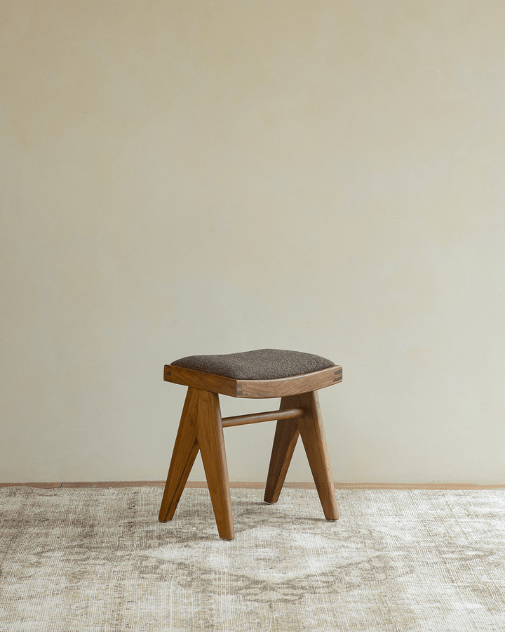 Chandigarh Easy Stool with minimalist design and grey upholstered seat on soft rug