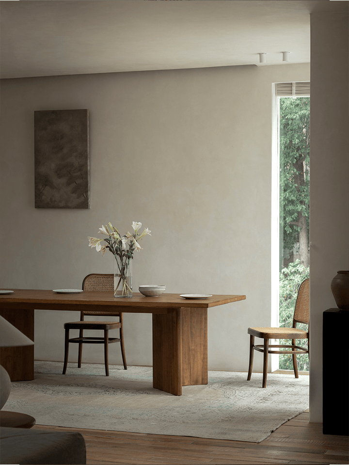 Minimalist Zephyr dining table with floral centerpiece and wooden chairs in a bright room