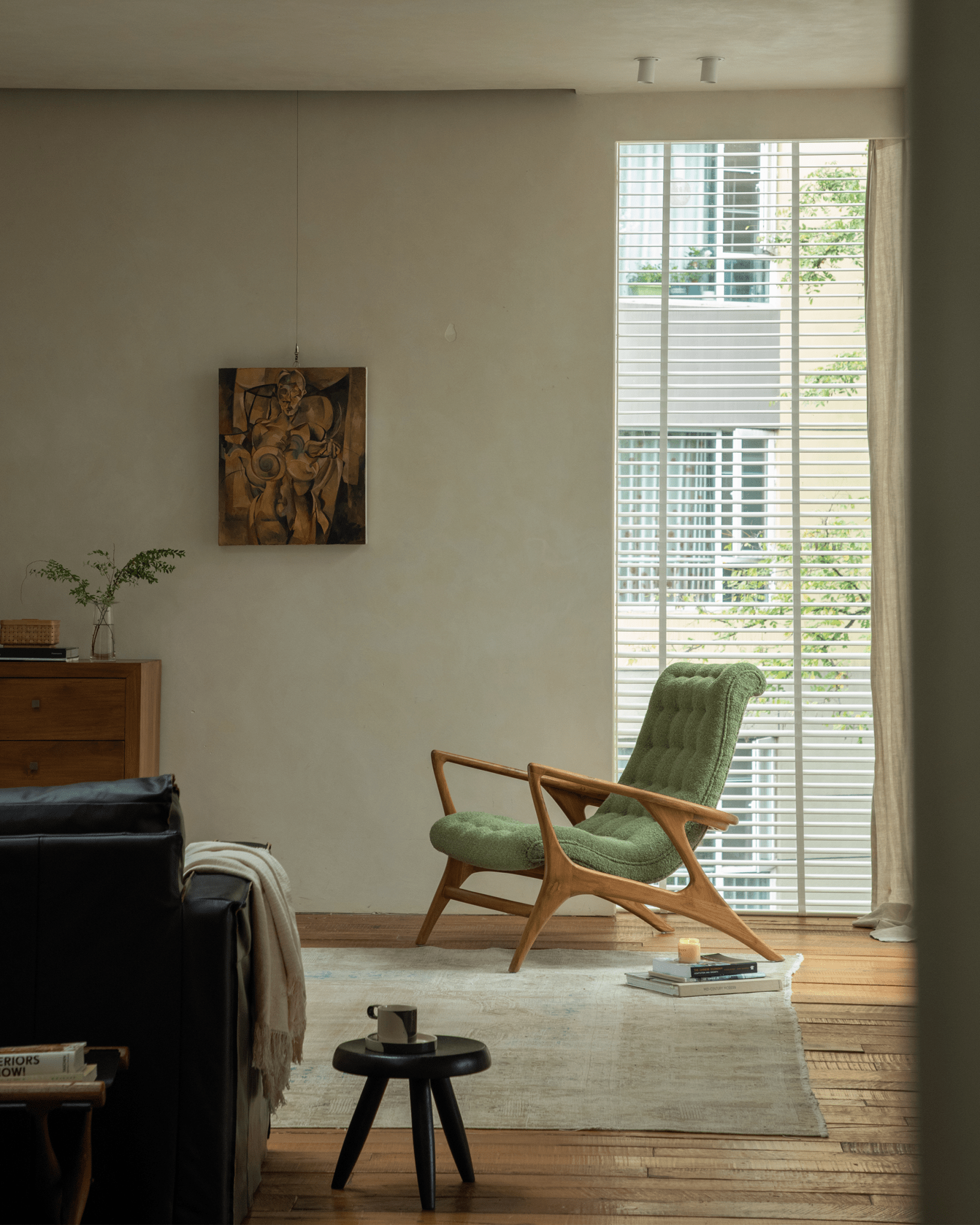 Green bouclé Kagan Lounge Chair with teak wood frame, mid-century modern design, in a cozy interior setting