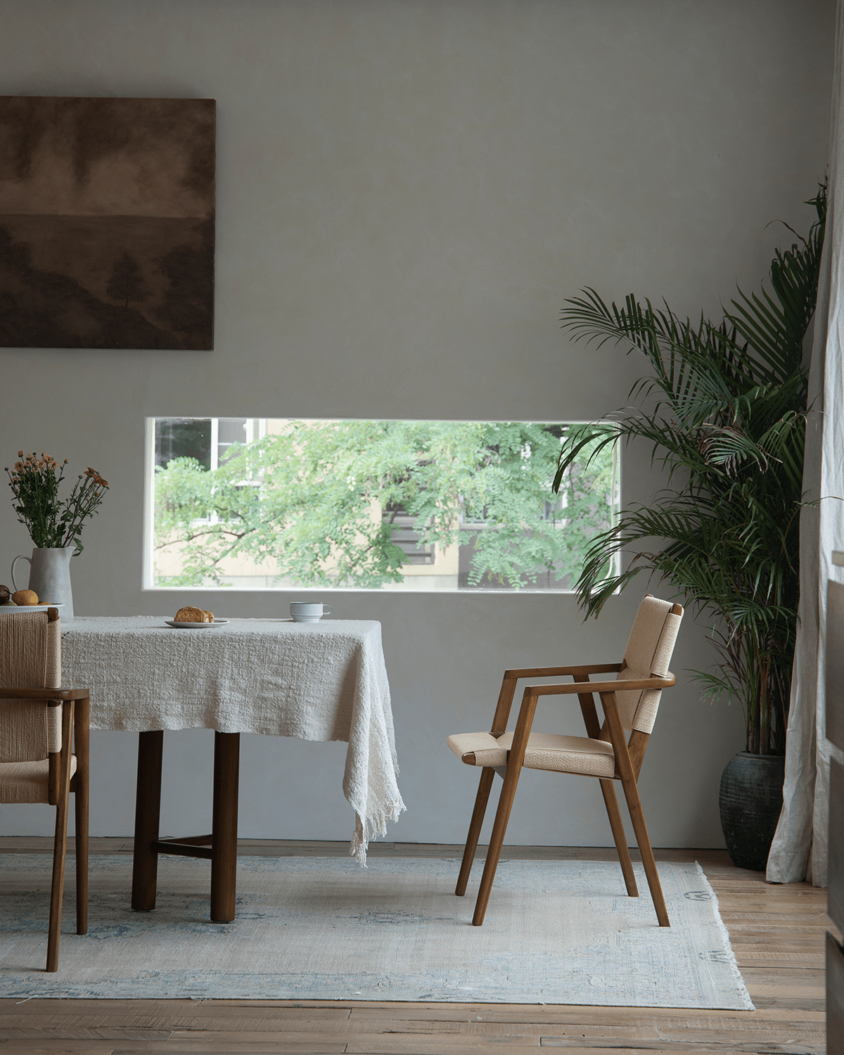 Louisa Chair in a dining room setting. Teak frame and woven seat chairs. Mid-Century Modern design.