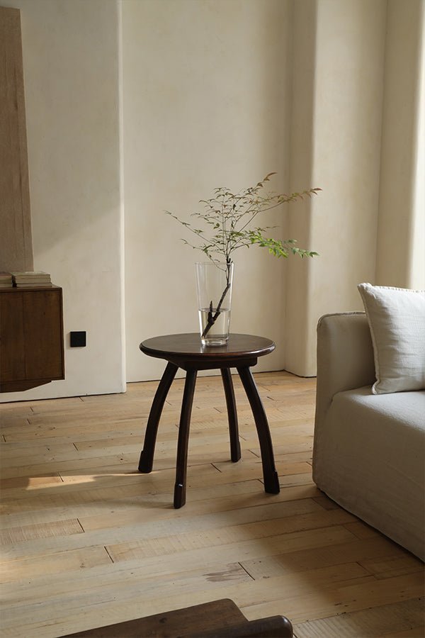 Ele Round Side Table with a simple vase and branches in a bright, modern living room.