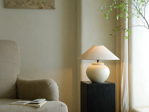 Clay moon lamp on black pedestal beside beige sofa in modern vintage living room
