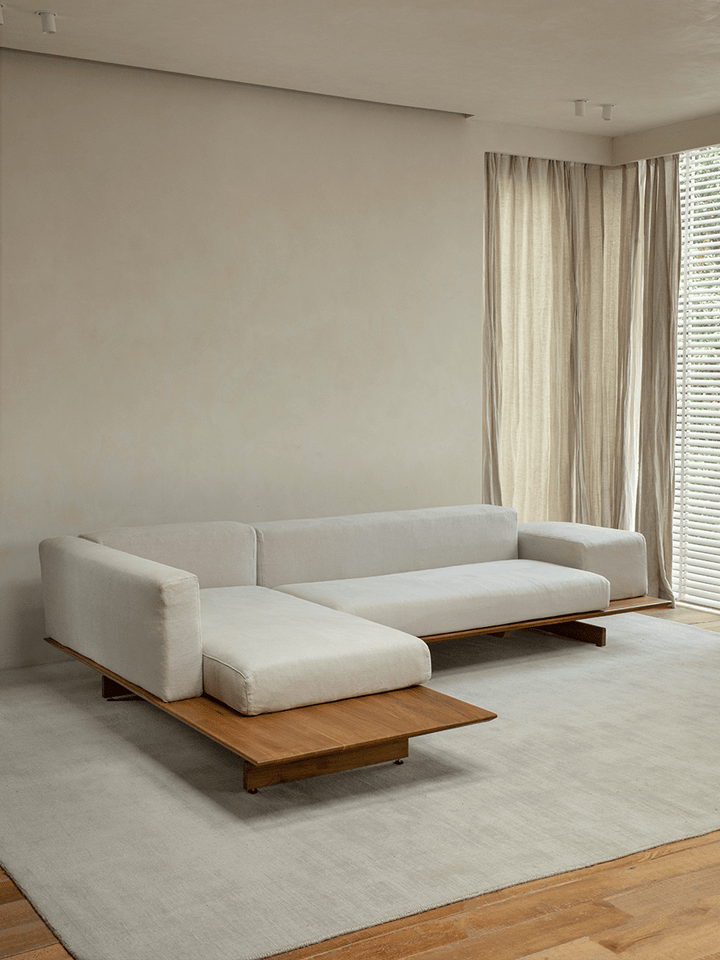 Contemporary linen modular sofa with teak base in a bright minimalist living space